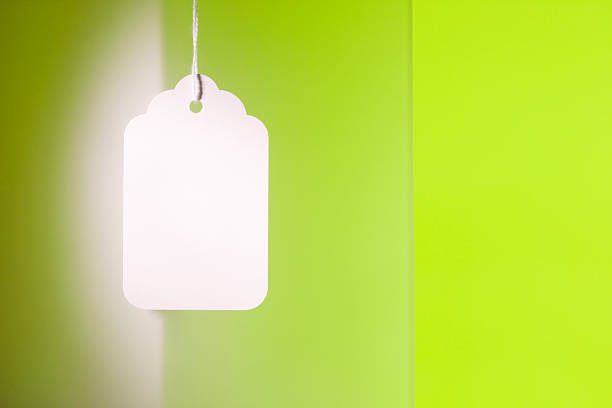 A blank white price tag or sign label hanging on a spring green background, as a concept for early bird sales or merchandise pricing. 