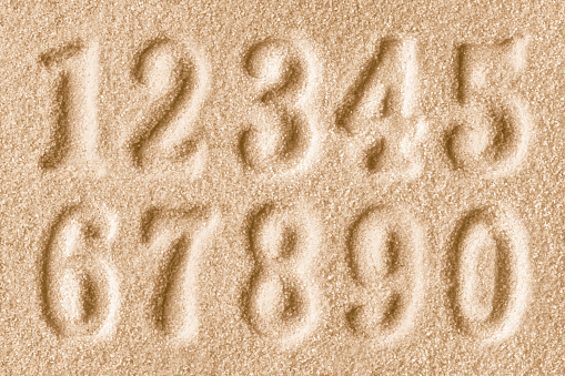 Imprints of numbers on a bright golden sand background