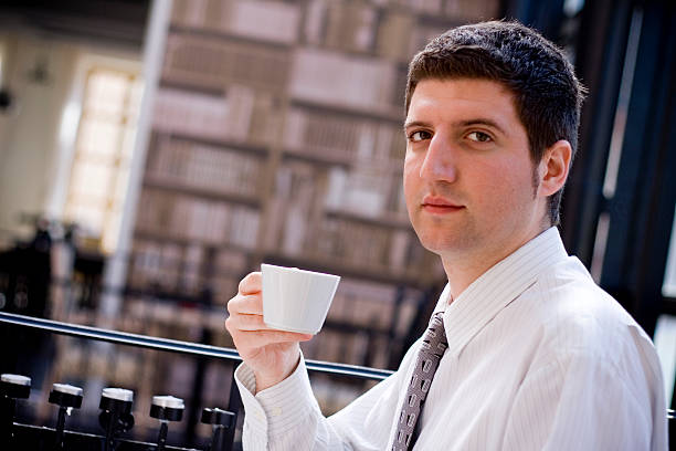 Businessman having a break in cafe Young attractive businessman drink a coffee on break. He is looking in camera. georgijevic stock pictures, royalty-free photos & images