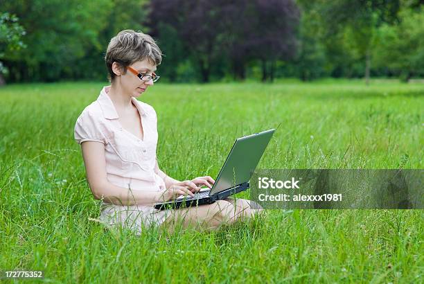 Photo libre de droit de Fille Avec Ordinateur Portable Se Trouve Sur Lherbe Verte Dans Le Parc banque d'images et plus d'images libres de droit de Adolescence