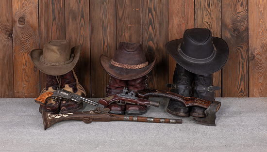 cowboy hat, boots and gun on a wooden floor