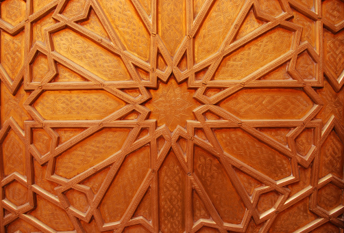 A detailed view of a polished-brass door decorated in ornate arabesque motifs.
