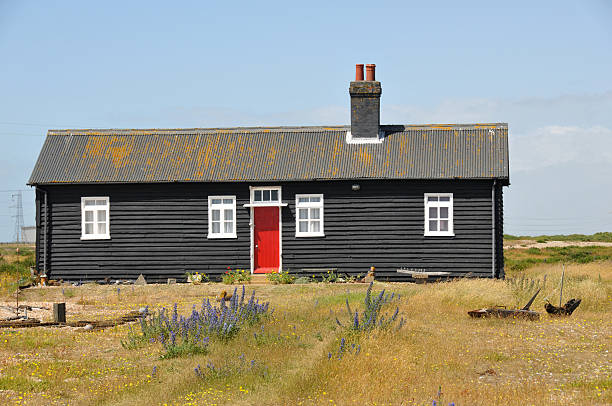 Black wooden holiday home in a field with dark and stormy clouds above