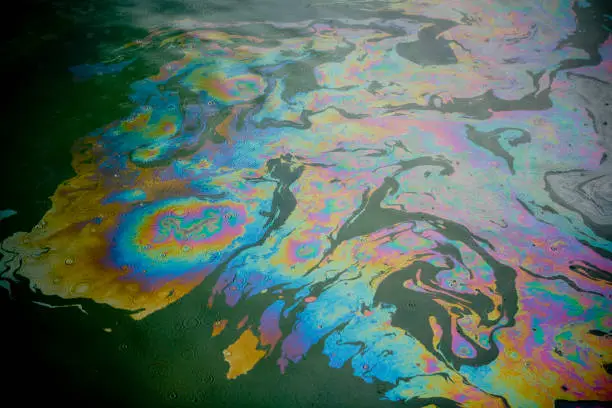 Diesel oil spill on the water surface during a light rain storm.