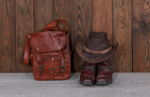 cowboy hat, boots and leather bag on the wooden floor