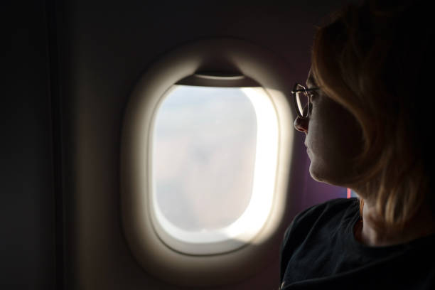 istock Woman looking throw the airplane window 1727788929