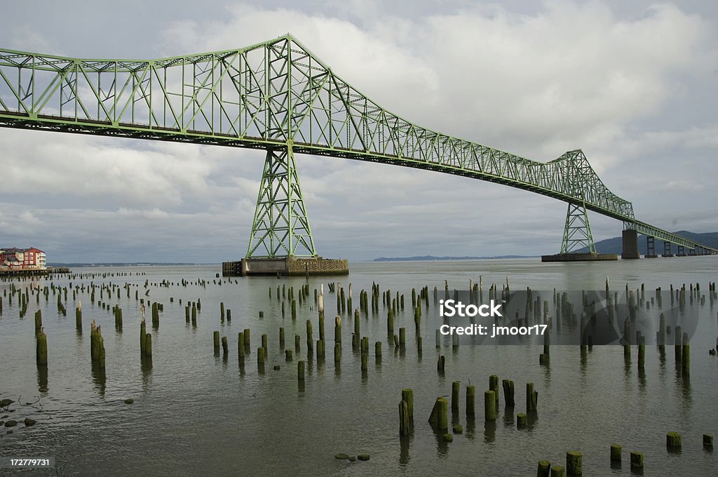 Astoria Oregon Bridge Morning This magnificent bridge crosses from Oregon to Washington State. Crossing the Columbia River this bridge provides a major transportation route. The Piers in the water reflect a time past and ferry service. Astoria - Oregon Stock Photo