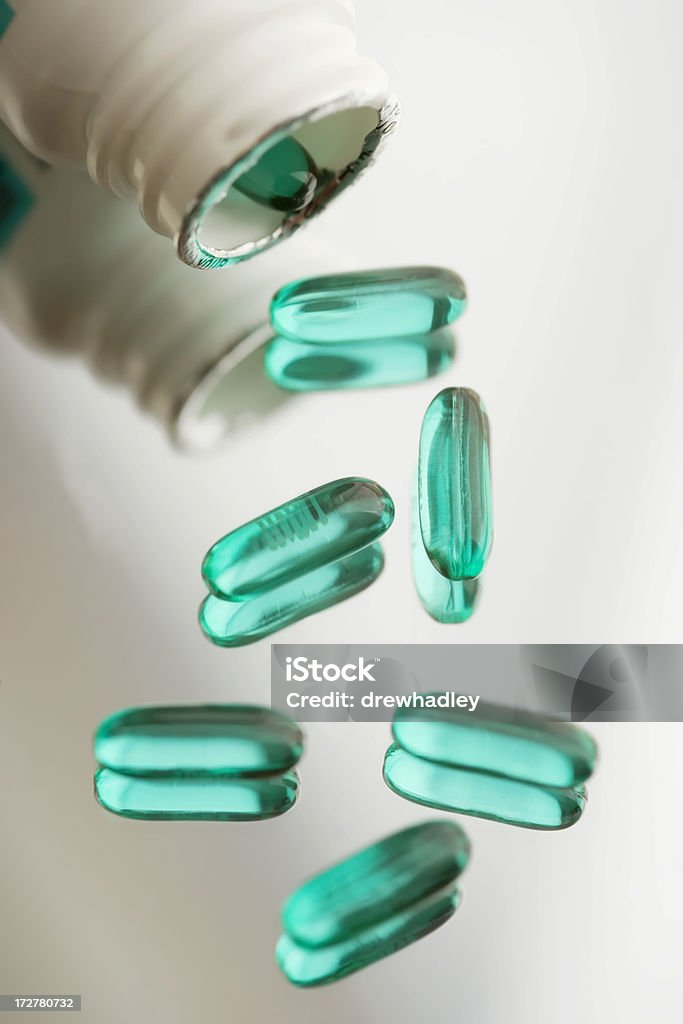 Prescription Drugs, Advil's on reflective surface. Bottle of prescription pain killers spilt on reflective surface. Advil. Pharmaceutical Industry. Vertical. Beauty Stock Photo