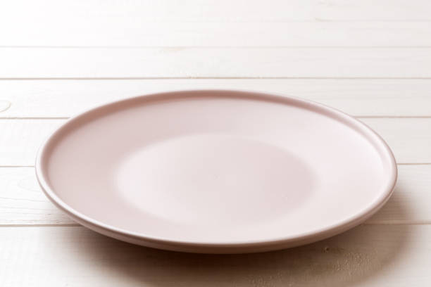 istock Perspective view of empty pink plate on wooden background. Empty space for your design 1727809171