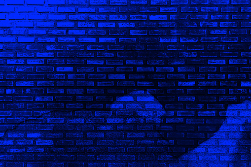 Dark blue purple old brick wall. Toned colorful grunge background. Space. Design. Cracked, broken, crumbled. Color gradient. Rough backdrop.
