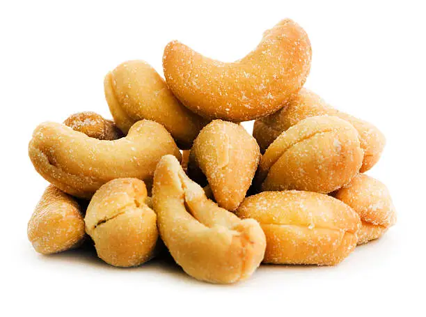A stack of roasted, salted cashew nuts. The heap of food is a crunchy snack that may be grown organically and may be an ingredient of a healthy eating diet, as a protien source. Cut out and isolated on a white background.