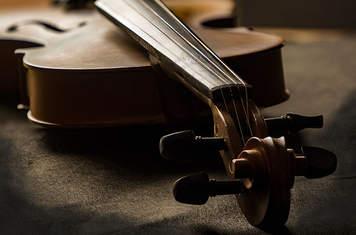 Violin in vintage style on wood background. The abstract art design background of violin on wooden timber board,blurry light around,show front side of instrument