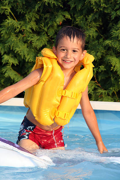 criança vestindo uma jaqueta amarela na piscina - life jacket equipment safety jacket - fotografias e filmes do acervo