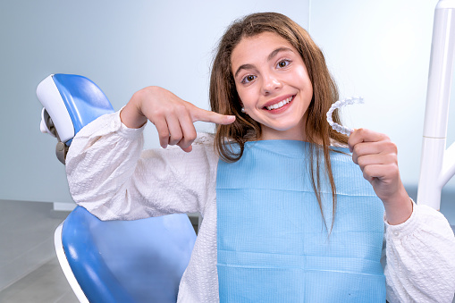 Teenage girl goes to the dentist to receive modern orthodontic treatment to correct the alignment of her teeth