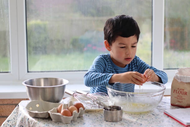 istock Child breaking eggs in to a glass bowl for making pancake batter for pancake day. 1727854953
