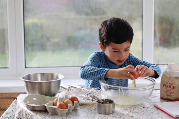 istock Child breaking eggs in to a glass bowl for making pancake batter for pancake day. 1727854954