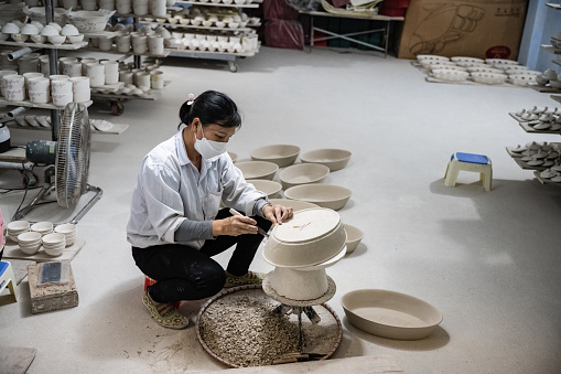 Bat Trang, Vietnam - November 10, 2022: view on woman working in vietnamese ceramic manufacture