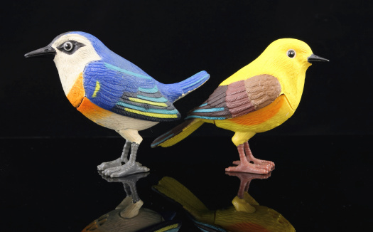 A pair of novelty plastic birds ignoring each other on a black background part of a series