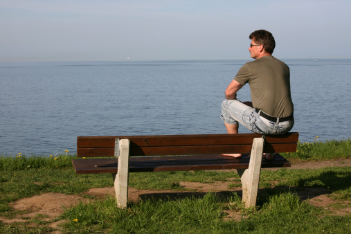 a man sits on a bench and looks at the sea