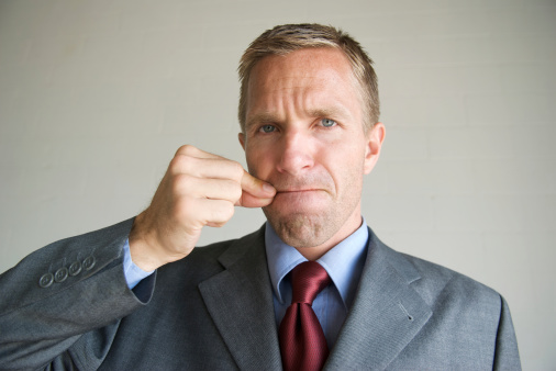 Businessman looks at the camera with a serious face as he zips his mouth closed