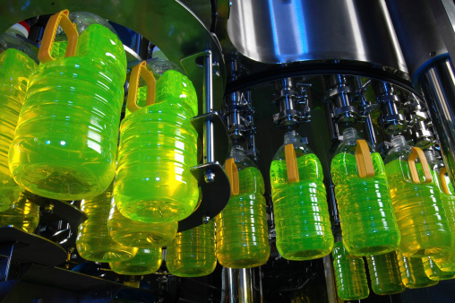 Factory machine producing and filling bottles with liquid (with blue highlights).