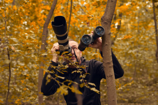 istock Man using binoculars and camera for birdwatching and other observing animals in nature. 1727886412