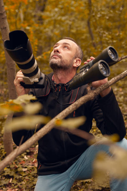 istock Man using binoculars and camera for birdwatching and other observing animals in nature. 1727887496