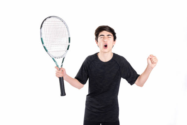 un adolescent joue au tennis et célèbre un point avec les mains levées. photographie prise dans un studio avec un fond blanc - tennis child athlete sport photos et images de collection