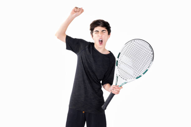 un adolescent joue au tennis et célèbre un point avec les mains levées. photographie prise dans un studio avec un fond blanc - tennis child athlete sport photos et images de collection