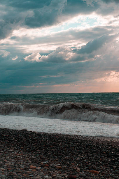 istock a cloud-covered sky over a raging sea with waves crashing on the shoreline pebbles 1727908830