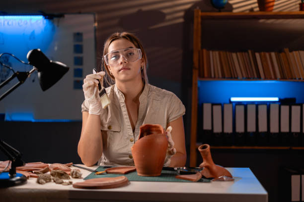 istock Archeologist working late night in office with brush and old vase 1727909050