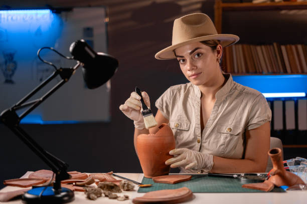istock Archeologist working late night in office with brush and old vase. 1727909053