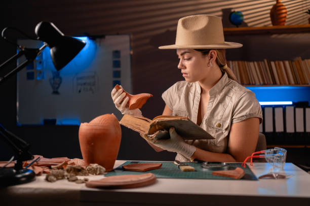 istock Archeologist reading old book working late night in office and studying amphora 1727909060