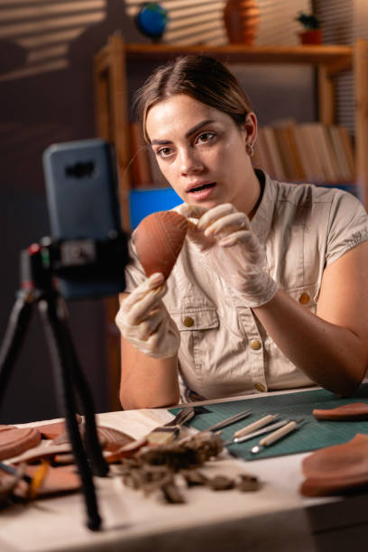 istock Female archaeologist doing research, uses smartphone to share discovery ancient civilization culture artifacts with followers in Internet 1727909073