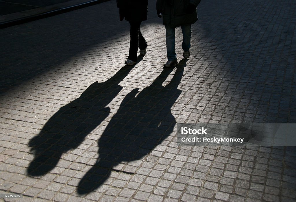 Amigos na sombra caminhada em ruas de paralelepípedos - Foto de stock de Sombra royalty-free