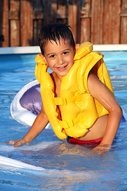 criança vestindo uma jaqueta amarela na piscina - life jacket equipment safety jacket - fotografias e filmes do acervo