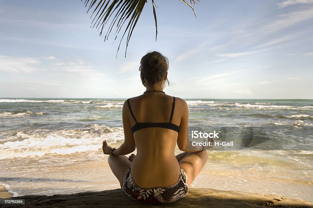 Femme pratiquant Yoga sur la plage dans la Posture du lotus - Photo de Chaleur libre de droits