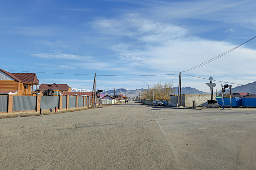 Northern Mongolia. Empty street intersection. City of Ulgiy. Houses of the street stretching into the distance to the mountains, Mongolian people on the street are busy with their worries.