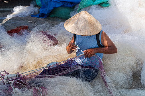 A man knitting fishing net with floats in Hon Ro dock, Nha Trang city, Khanh Hoa province, central Vietnam