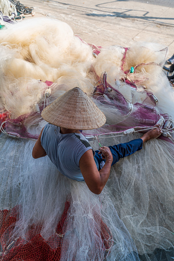 A man knitting fishing net with floats in Hon Ro dock, Nha Trang city, Khanh Hoa province, central Vietnam