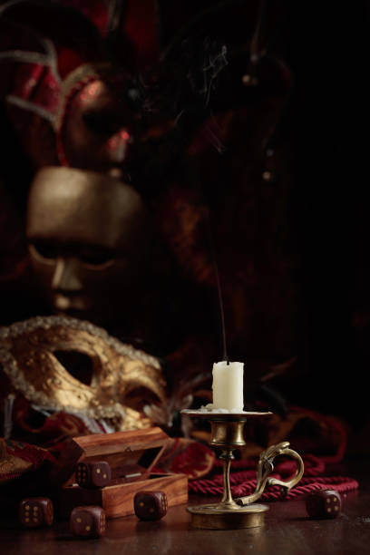 istock Extinguished candle, dice, and carnival masks on an old wooden table. 1727943213