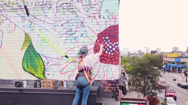 Young Caucasian woman creating outdoor mural on the roof top