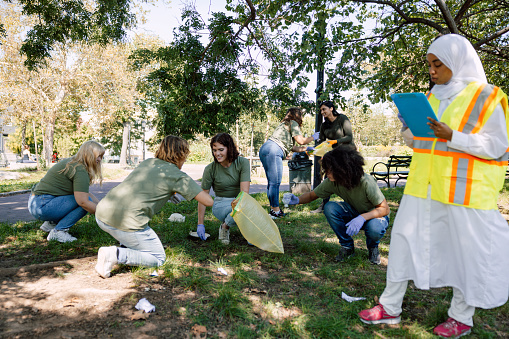 Group of multi-ethnic people, people volunteering cleaning garbage and collecting plastic bags and other general trash in a public park