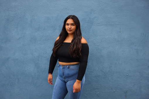 Young Body Positive woman with simple blue background.
