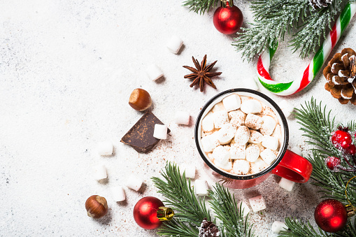 Christmas drink. Hot chocolate with marshmallow and gingerbread cookies with holiday decorations at white table. Top view with copy space.