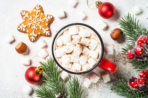 Christmas drink. Hot chocolate with marshmallow and gingerbread cookies with holiday decorations at white table. Top view with copy space.