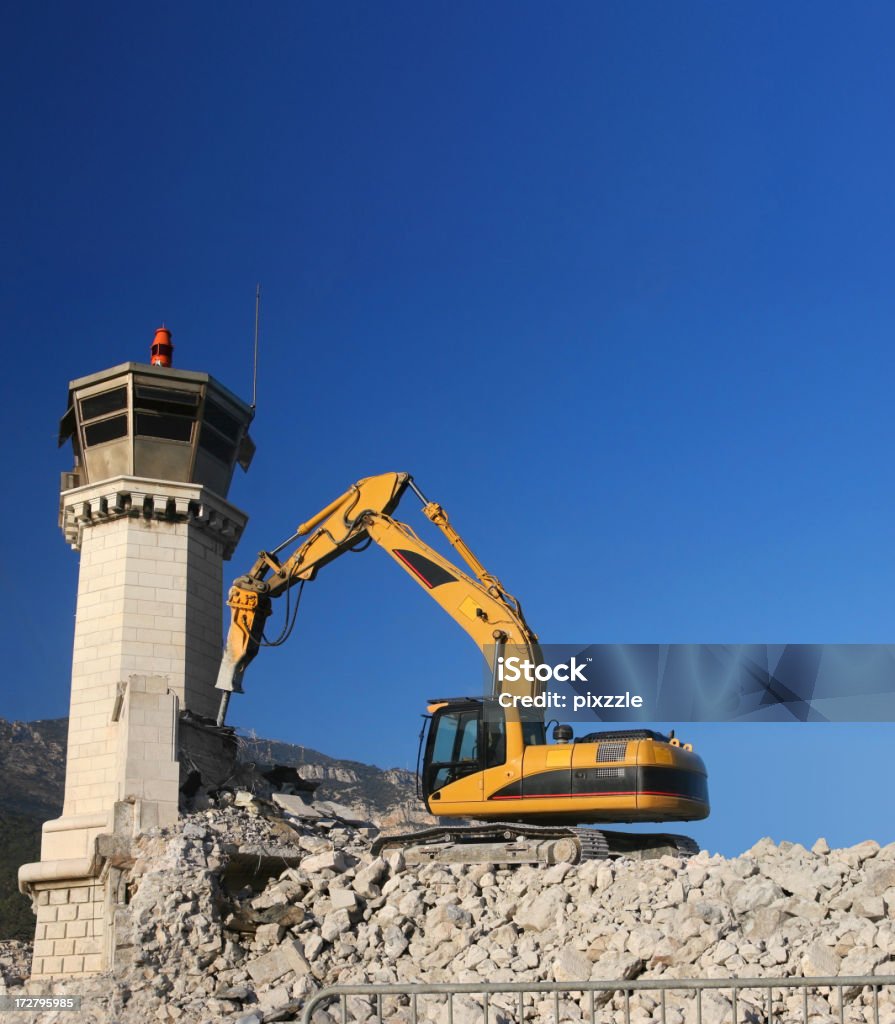 Demolition of tower by hammer bulldozer Demolition of the beacon at the entrance to Monaco harbor; January 2006. Port has been extended and the old outer wall removed. Backhoe Stock Photo