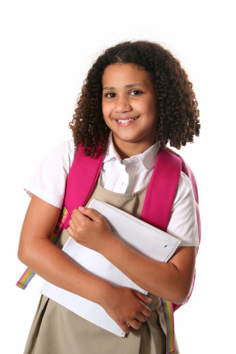 Little girl in school uniform with backpack and notebook
