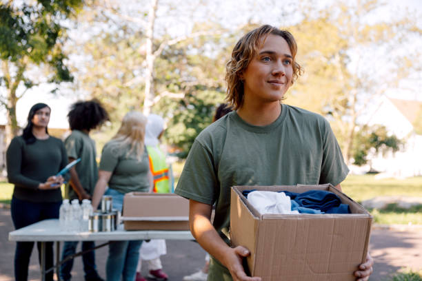 istock Young man volunteer holding a box full of clothes 1727966048