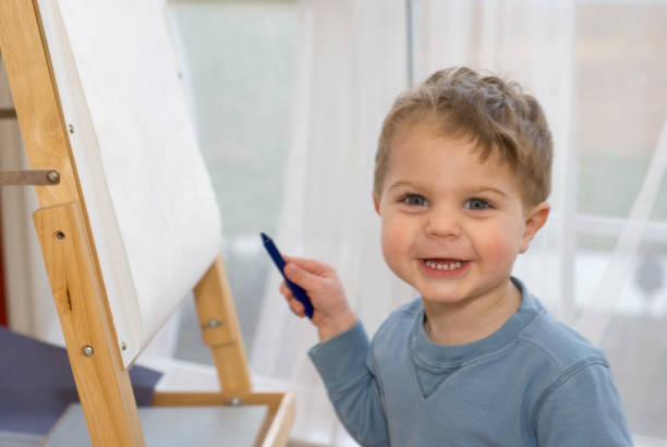 istock Cure toddler draws with crayon on easel 172796629